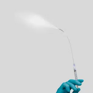 Hånd i blå handske aktiverer MADgic Laryngo-Tracheal, så væske forstøves til intranasal medicinadministration.