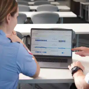 To personer gennemgår HLR-data i RescueNet CaseReview på en bærbar computer i et undervisningslokale.