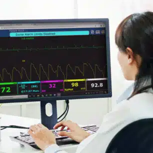 Person følger patientdata i RescueNet Live telemedicinsk software på skærm på kontor.