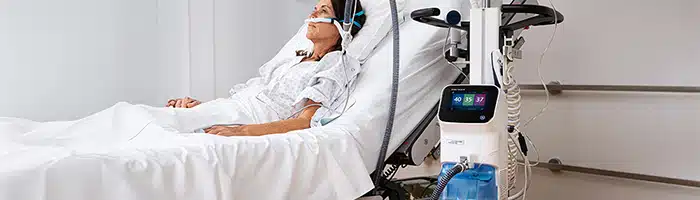 Dame ligger I en hospitalsseng tilsluttet til HAMILTON-HF90 system til high flow iltterapi